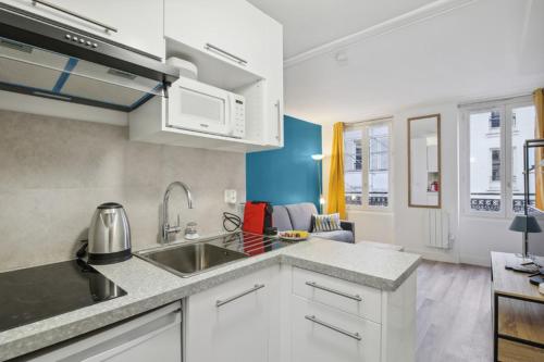 une cuisine avec un évier et un micro-ondes dans l'établissement 513 Suite Marie - Superbe logement Quartier Marais, à Paris