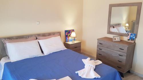a bedroom with a blue bed with a dresser and a mirror at Rantos P. Cottage in Dragotiná