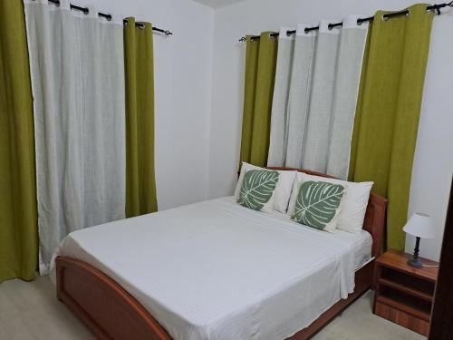 a bedroom with a bed with green curtains at Studio Ametisse in Belle Mare
