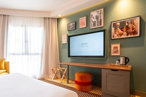 a bedroom with a flat screen tv on a green wall at Mercure Shéhérazade Rabat in Rabat