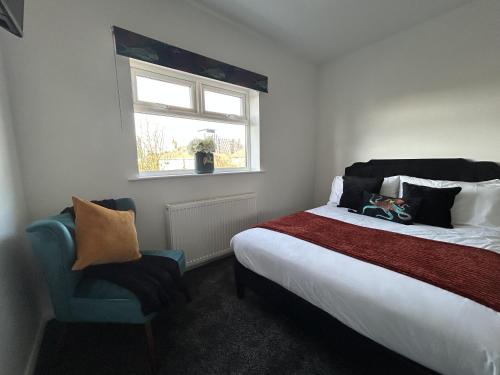 a bedroom with a bed and a window and a chair at The Cotswold Cornerstone in Billingham