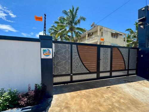 a fence with a gate with a wooden door at Villa Dei Niuri Mauritius in Pointe aux Piments