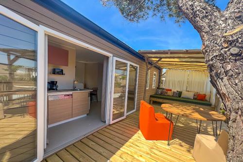 une terrasse avec une table, des chaises, une table et un arbre dans l'établissement Camping de la Clape Village - Maeva, au Cap d'Agde