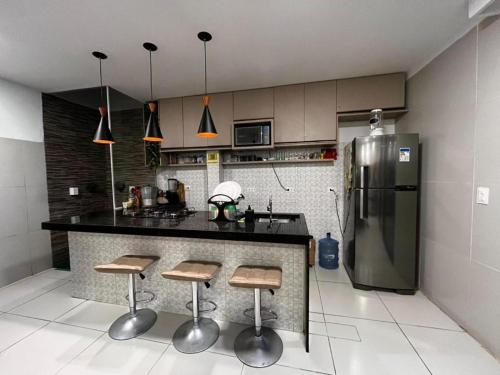 a kitchen with a counter with stools and a refrigerator at Casa Gravata in Gravatá