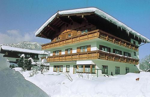 a large wooden building with snow on top of it at Pension Obermoser in Sankt Johann in Tirol