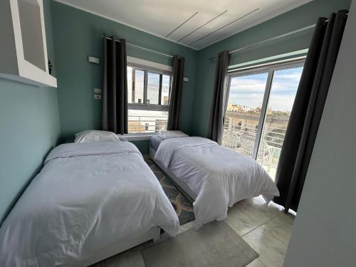 Dos camas en una habitación con una gran ventana. en Nile Spirit Sunrise, en Luxor