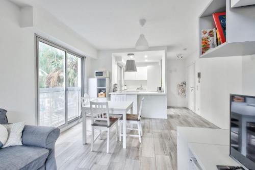 Il dispose d'une cuisine blanche et d'un salon avec une table et des chaises. dans l'établissement Flat with balcony 15min from Promenade des Anglais, à Nice