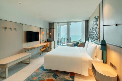 a hotel room with a white bed and a balcony at Holiday Inn Pattaya by IHG in Pattaya Central