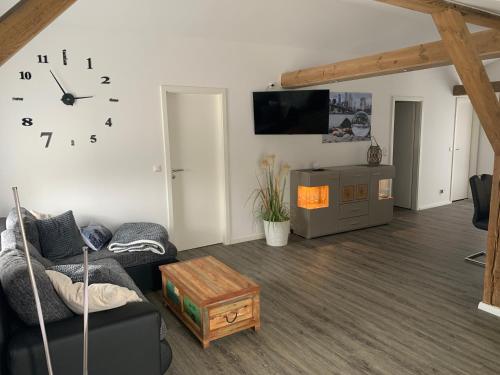 a living room with a couch and a clock on the wall at FEWO Hoppegarten in Hoppegarten