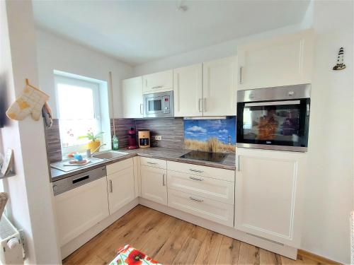 a white kitchen with white cabinets and a tv at Ferienwohnung Mohnblume in Sassnitz