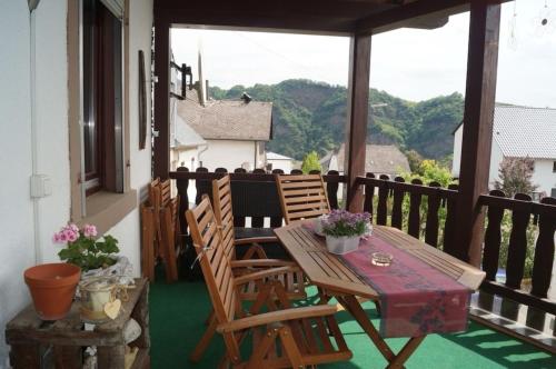 a porch with a wooden table and chairs on a balcony at familienfreundliche Ferienwohnung Weingarten in Piesport in Piesport