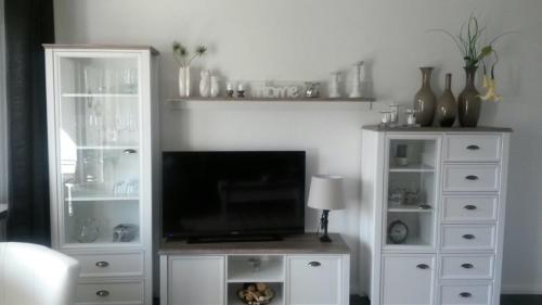 ein Wohnzimmer mit einem TV und einem weißen Entertainment-Center in der Unterkunft Fewo 8 Steffens in Goslar