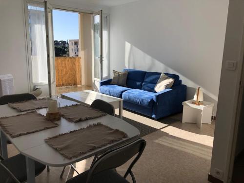 un salon avec une table et un canapé bleu dans l'établissement Confortable appartement 5 pers, 900m plage et commerces, à Sainte-Maxime