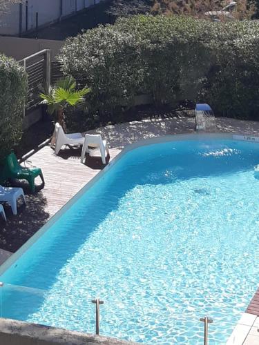 une grande piscine bleue avec 2 chaises longues dans l'établissement Beau Studio Prado Plage Parc Piscine Stade, à Marseille