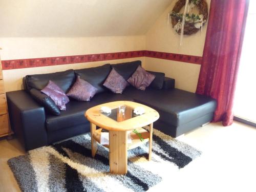 a living room with a black couch and a table at Ferienwohnung PANTEN in Neukirchen