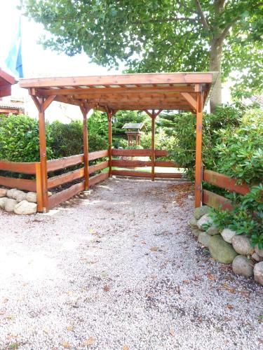 a wooden pavilion with a fence and a tree at Ferienwohnung PANTEN in Neukirchen
