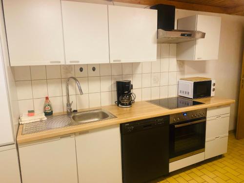 a kitchen with white cabinets and a sink and a microwave at Ferienwohnung Stargardt in Bad Münder 6 Personen Soutterain in Bad Münder am Deister