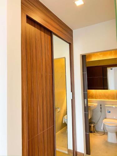 a bathroom with a toilet and a wooden door at The Astra Luxury Condo near old town in Chiang Mai