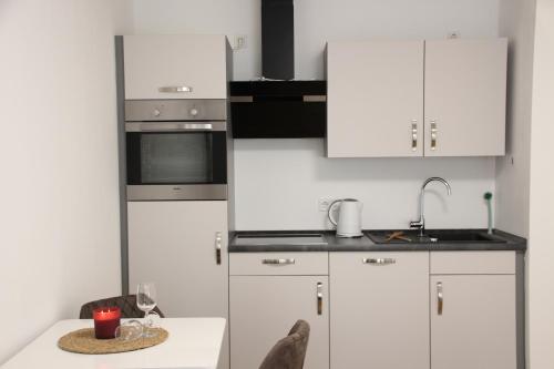 a kitchen with white cabinets and a table with a wine glass at Casa Kronengarten Nr 5 in Hilden
