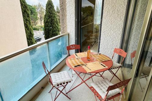 une table et des chaises assises sur un balcon avec vue sur la piscine dans l'établissement T2 in La Favière - 5 minutes from the beach, à Bormes-les-Mimosas