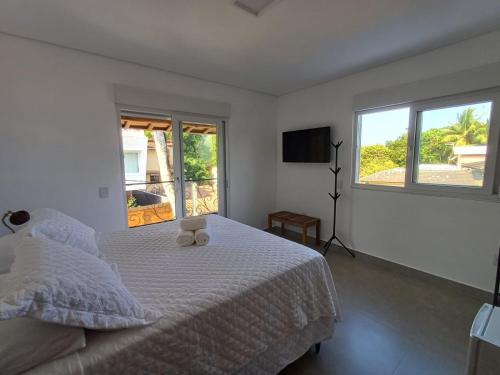 um quarto branco com uma cama e duas janelas em Suítes Mucugê em Arraial d'Ajuda