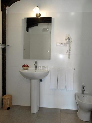 a bathroom with a sink and a mirror and a toilet at Posada Ansorena in Santillana del Mar