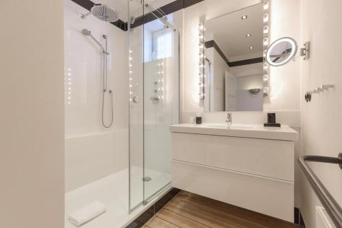 a white bathroom with a shower and a sink at Die Schlosserei in Westerland