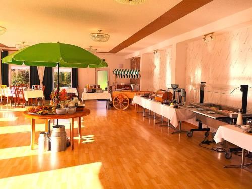 Harzhotel Grünett في لانغلسهايم: غرفة كبيرة بها طاولة عليها مظلة خضراء