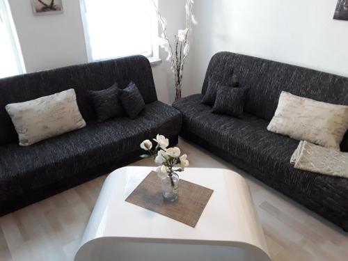 a living room with a black couch and a coffee table at Ferienwohnung Weiland 60qm in Lutherstadt Eisleben