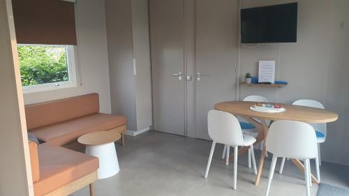 a small room with a table and white chairs at Campingland Ostsee - Mobilheim 76Strandhafer NEU! in Schashagen