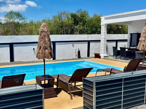 a swimming pool with chairs and a table and a patio at Villa Dei Niuri Mauritius in Pointe aux Piments