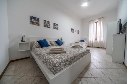 a white bedroom with a large bed with blue pillows at Gioia del Corso in Iesi