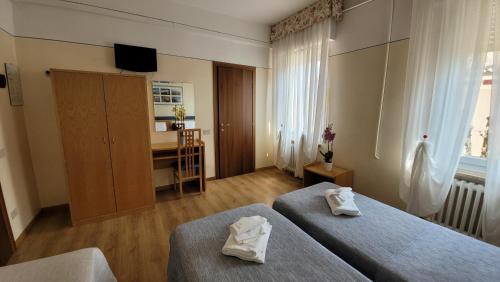 a hotel room with two beds and a desk at Hotel Montepiana in Mestre