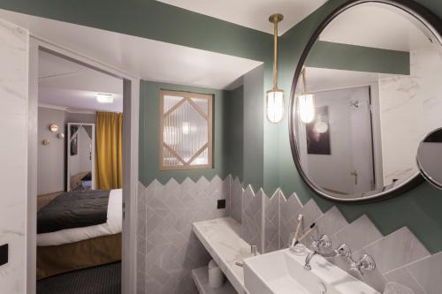 une salle de bain avec un lavabo, un miroir et un lit dans l'établissement Handsome Hotel, à Paris