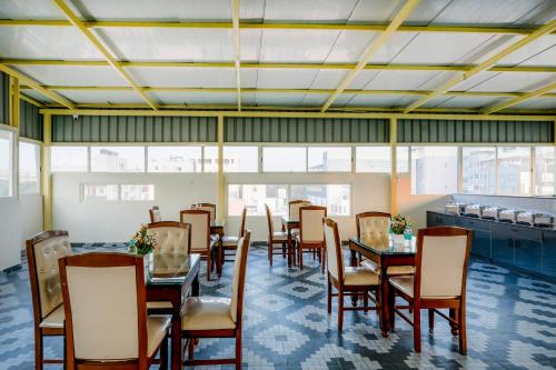 a dining room with tables and chairs and windows at R D HOTELS Peenya in Bengaluru