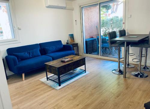 un salon avec un canapé bleu et une table dans l'établissement Superbe appartement climatisé avec wifi classé 3 étoiles à 50 m de la plage Le Lavandou, au Lavandou