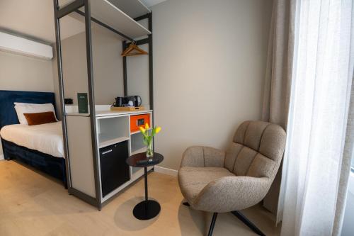 a bedroom with a bed and a chair and a mirror at Hotel Royal in Noordwijk