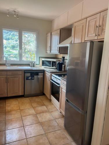 une cuisine avec des armoires en bois et un réfrigérateur en acier inoxydable dans l'établissement Belle villa avec piscine proche monaco, à La Turbie