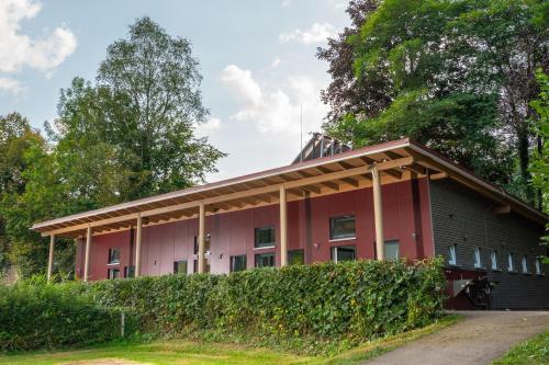 a red and black building with trees in the background at Camping Bad Liebenzell in Bad Liebenzell