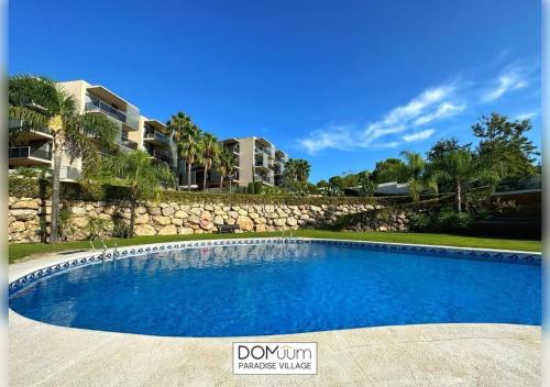 een groot blauw zwembad voor een gebouw bij DOMuum Holidays - PARADISE VILLAGE in Salou