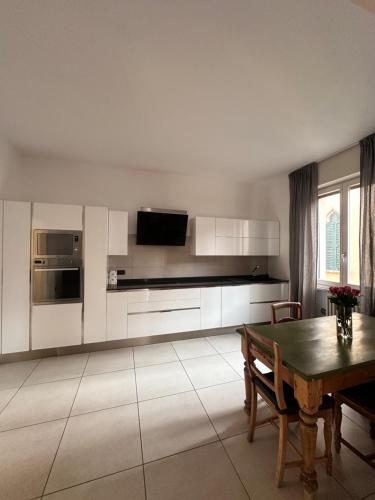 ヴェローナにあるCatullo 12の白いキャビネットと木製のテーブルのあるキッチン