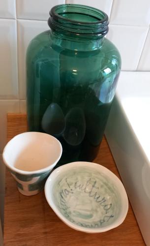 a green glass jar and a bowl on a table at Museo Grillo Camere d'Arte, dormire nel Museo in Arena Po