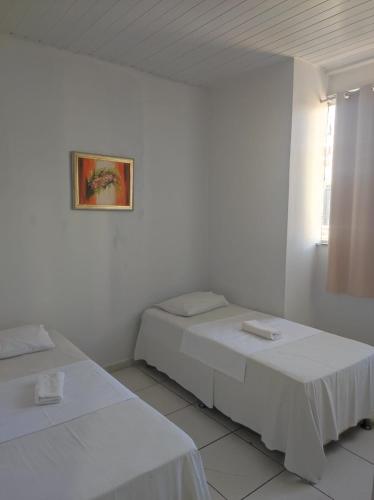 two beds in a white room with a picture on the wall at Shopping 44 Hotel in Goiânia