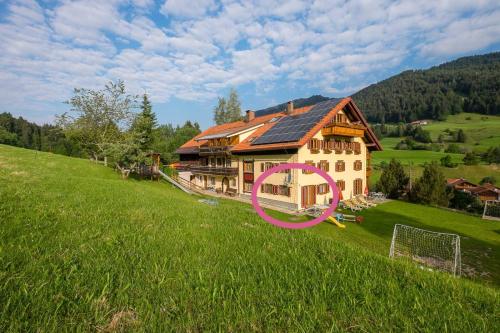 a large house on a grassy hill with a purple symbol at Gästehaus Schlegel in Gunzesried