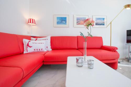 a red couch in a living room with a white table at Windeby 7T in Wenningstedt