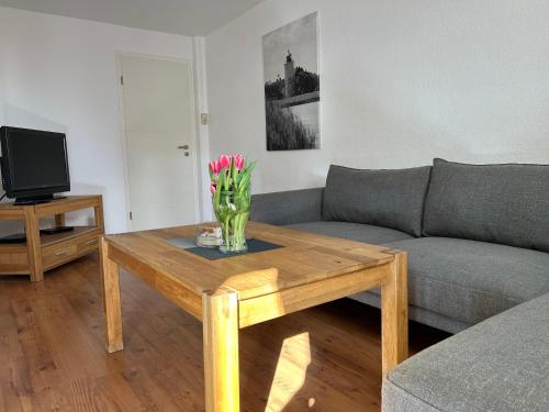 a living room with a table with a vase of flowers on it at Ferienwohnung Süd in Fehmarn