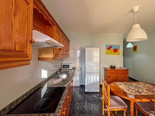 a kitchen with wooden cabinets and a table and a refrigerator at Lightbooking Luymar con piscina Villa de Mazo in Villa de Mazo