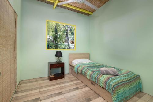 a bedroom with a bed and a table and a picture at Cabinas Sede Villalobos, 3Min from the Beach! Playa Chiquita in Punta Uva