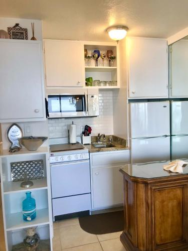 a kitchen with white cabinets and a white refrigerator at Ocean Breeze - Ocean Front at Symphony Beach Club! in Ormond Beach