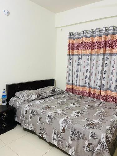 a bedroom with a bed and a curtain at Modern Furnished Apartment in Uttara Near Metro in Dhaka